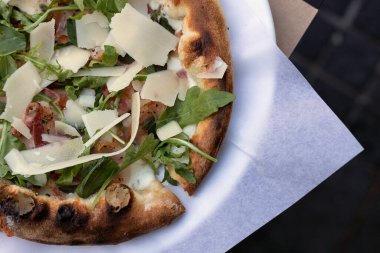 Beyaz bir tabakta domuz pastırması, roka, parmesan, mozzarella, fesleğen ve kekik soslu İtalyan pizzası. Bej arkaplan