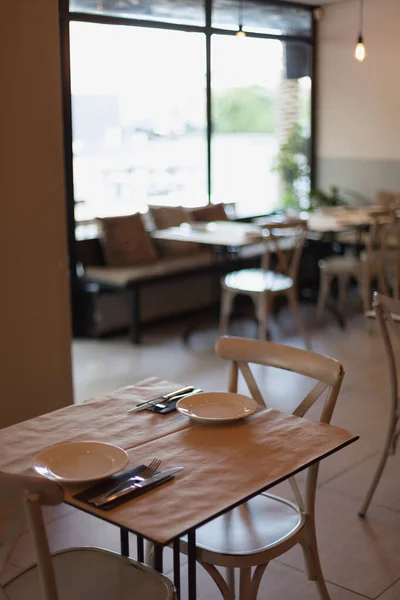 Lugar acogedor. una mesa dentro de un restaurante italiano con platos, cuchillos y tenedores —  Fotos de Stock