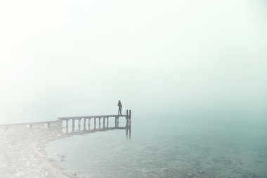 Man standing on a boardwalk in the fog clipart