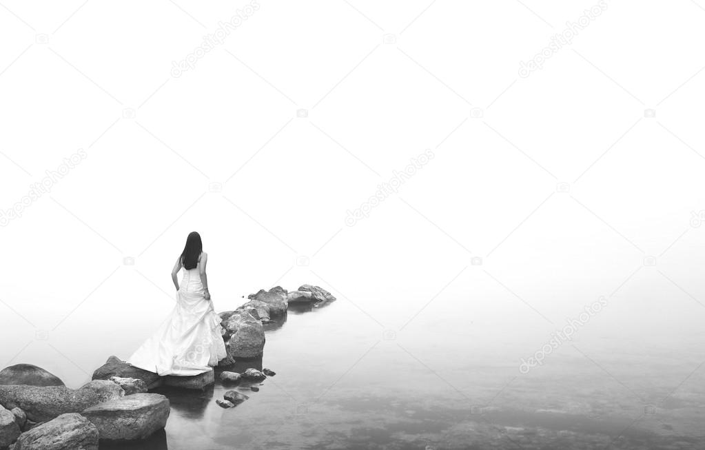 bride walking on the rocks in a mistic foggy lake