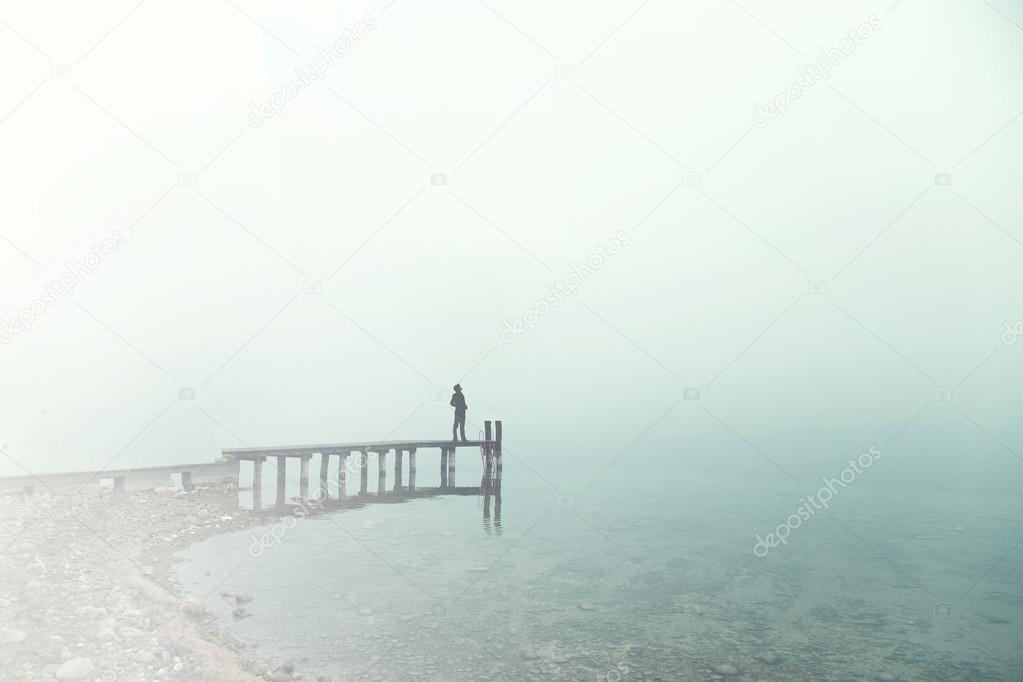 Man standing on a boardwalk in the fog