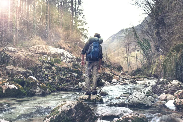 Hombre sintiendo la atmósfera del bosque cruzando el arroyo — Foto de Stock