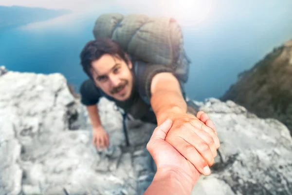 Adventurers helping each other to climb the mountain — Stock Photo, Image