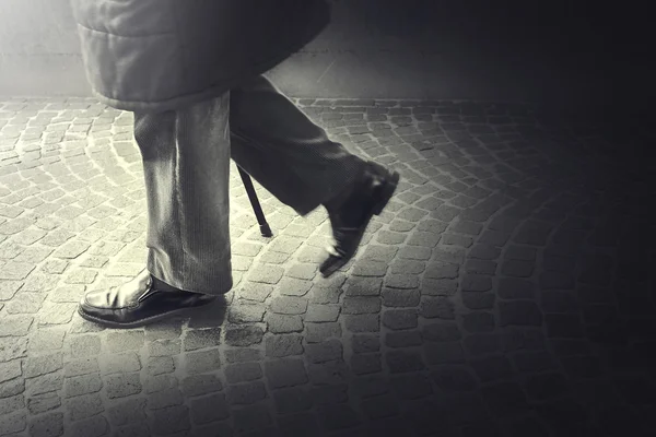 Viejo caminando con su palo hacia la luz — Foto de Stock