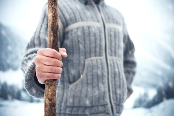 Hombre sosteniendo palo de madera en el frío invierno mientras nieva — Foto de Stock