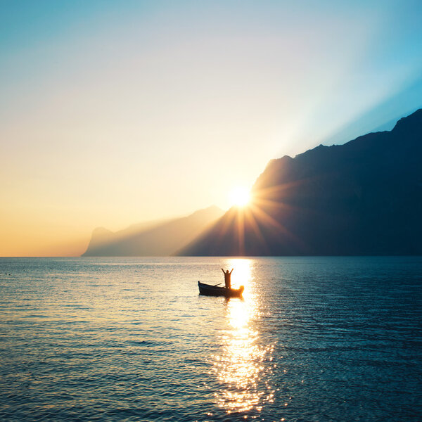 Blissed Man on a boat exulting at sunset