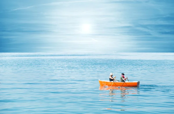 Pasangan mendayung bersama di perahu oranye di danau — Stok Foto