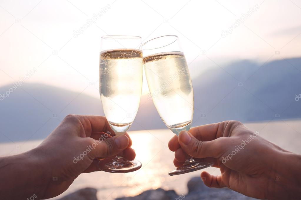 Lovers toast with wite wine at sunset