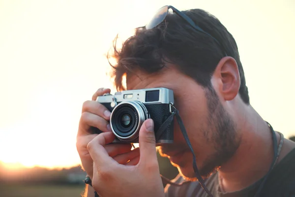 Чоловік стріляє з старовинної камери на заході сонця — стокове фото
