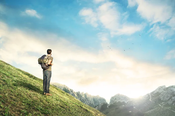 Homem descida observando paisagem montanhosa ao pôr do sol — Fotografia de Stock