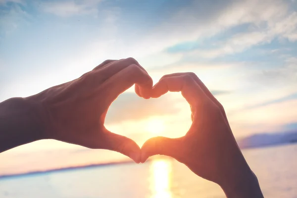 Heart shape made with hands at sunset — Stock Photo, Image