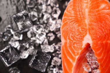 Siyah taş bir tahtanın üzerinde buzlarla dilimlenmiş somon balığı. kırmızı balık. 