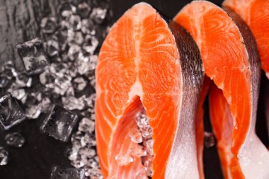 Siyah taş bir tahtanın üzerinde buzlarla dilimlenmiş somon balığı. kırmızı balık. 