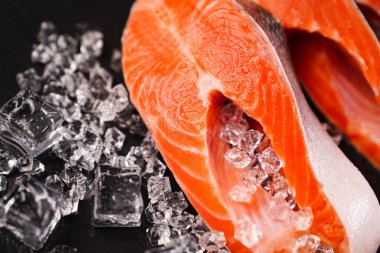 Siyah taş bir tahtanın üzerinde buzlarla dilimlenmiş somon balığı. kırmızı balık. 