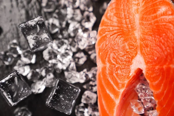 Siyah taş bir tahtanın üzerinde buzlarla dilimlenmiş somon balığı. kırmızı balık. 