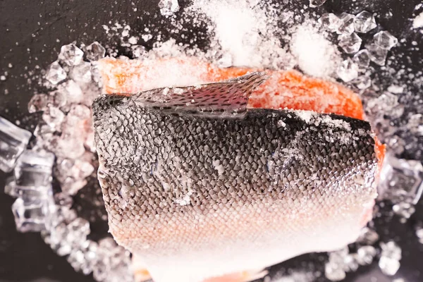 Zalm op een zwarte stenen plank met ijsblokjes. rode vis. — Stockfoto