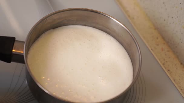 Το γάλα βράζει σε μια κατσαρόλα στη σόμπα και χύνεται στη σόμπα. — Αρχείο Βίντεο