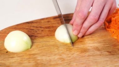 Tahta kesme tahtasının üzerinde bıçaklı bir soğanla dilimleme..