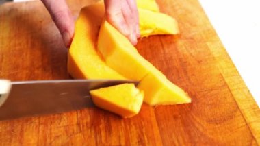 Soyulmuş kabak dilimleri kesme tahtasıyla parçalara ayrılmış.