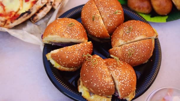 Hamburgery przecięte na pół dla dzieci podczas wakacji na świeżym powietrzu. fast food. — Wideo stockowe