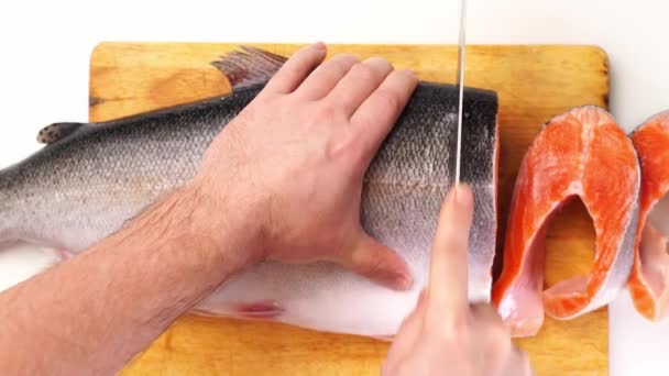 Rainbow trout is cut into steaks with a large knife on a wooden cutting Board. — Stock Footage Rainbow trout is cut into steaks with a large knife on a wooden cutting Board. Stock Footage