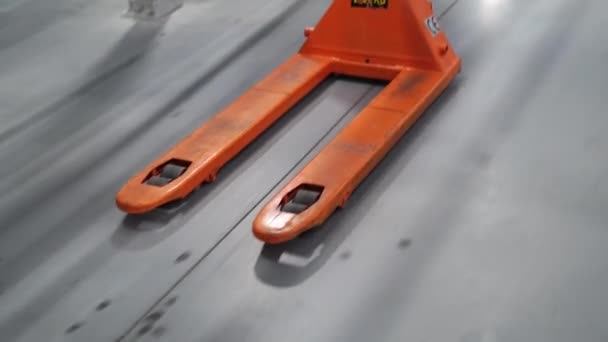 De lader trekt de hydraulische trolley op de grijze vloer. — Stockvideo