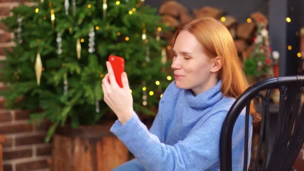 女性はクリスマスツリーの近くのビデオリンクで話してる。友達を祝福し — ストック動画