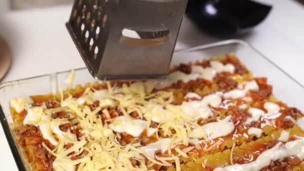Zmielić ser na lasagne w naczyniu do pieczenia. zapiekanka z makaronem z sosem. — Wideo stockowe