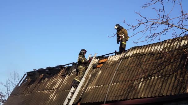 Пожарные работают на крыше сгоревшего здания. — стоковое видео