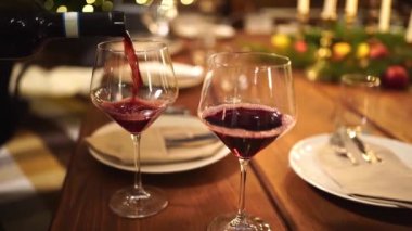 Az ışık. Mum ışığında akşam yemeği için şişeden şarap dök..