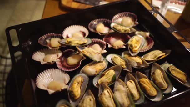 Low light. mussels and scallops are spread on a baking sheet to bake in the oven — Stock Video
