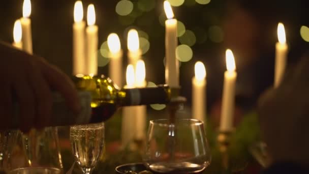 Nedostatek světla. ve sklenici nalévat víno z láhve k večeři při svíčkách. — Stock video