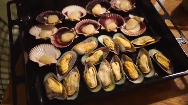 Low light. mussels and scallops are spread on a baking sheet to bake in the oven — Stock Video