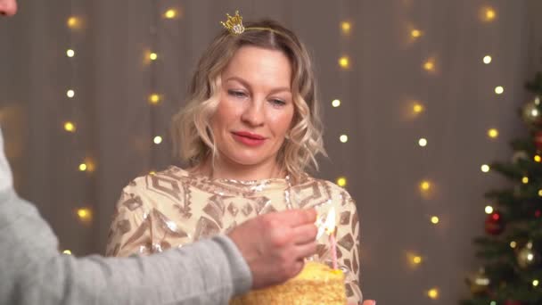 Schöne blonde Frau in kleiner Krone auf dem Kopf mit Geburtstagstorte und Kerzen. — Stockvideo