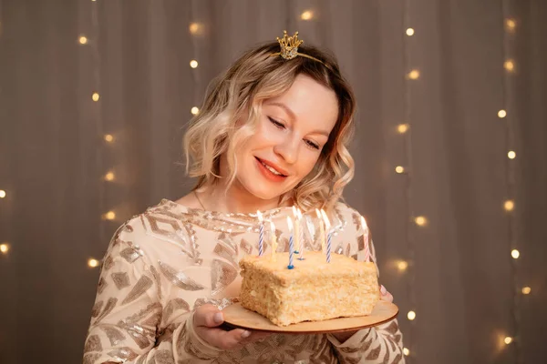 Mulher loira bonita em pequena coroa na cabeça com um bolo de aniversário e velas. — Fotografia de Stock