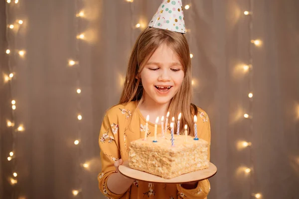 Glad flicka med födelsedagstårta. tradition att önska och blåsa ut eld — Stockfoto