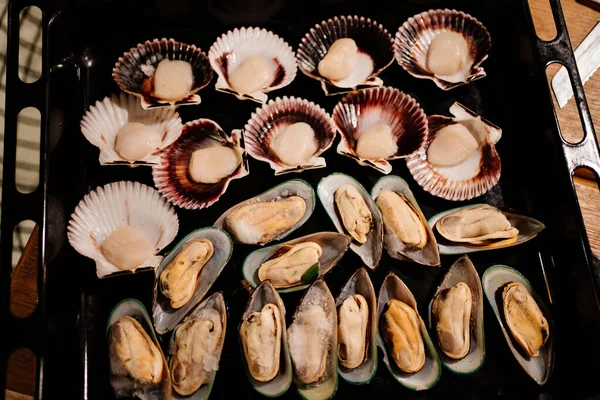 Low light. mussels and scallops are spread on a baking sheet to bake in the oven — Stock Photo, Image