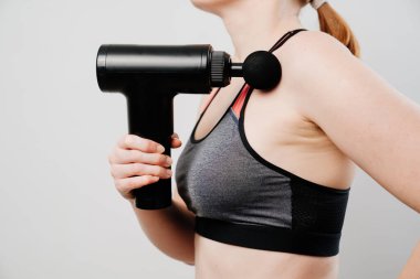 Kadının elinde masaj silahı var. tıbbi spor aygıtı. 