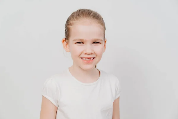 Little girl with collected hair in a white T-shirt stands on a white background — Stock Photo, Image