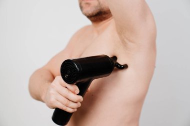 Adam masaj silahı kullanıyor. Tıbbi spor aleti eğitimden sonra kas ağrısının azalmasına yardımcı olur, yorgunluğun azalmasına yardımcı olur, vücudun sorunlu bölgelerini etkiler, cildin durumunu iyileştirir.