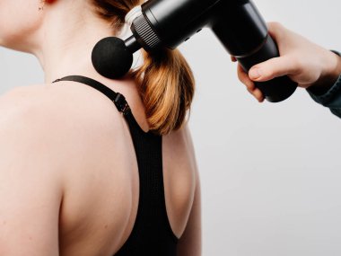 Kadın masaj silahı kullanıyor. Tıbbi spor aleti eğitimden sonra kas ağrısının azalmasına yardımcı olur, yorgunluğun azalmasına yardımcı olur, vücudun sorunlu bölgelerini etkiler, cildin durumunu iyileştirir.