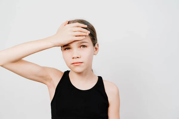 Ein Teenager in einem schwarzen T-Shirt hält ihre Hand auf der Stirn gegen ein weißes — Stockfoto