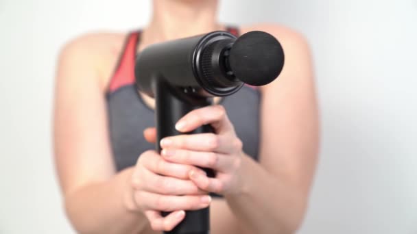Una donna ha una pistola da massaggio. dispositivo medico-sportivo funzionante. — Video Stock