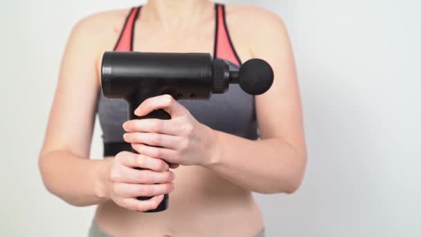 Femme tient un pistolet de massage. dispositif médical-sportif fonctionnant. — Video