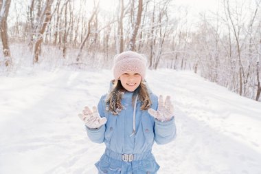 Bir kız kar toplarıyla oynadıktan sonra pembe eldivenlere yapışmış kar gösteriyor..