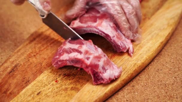 Çiğ domuz kaburgaları tahta bir kesme tahtasının üzerinde bıçakla kesilir.. — Stok video