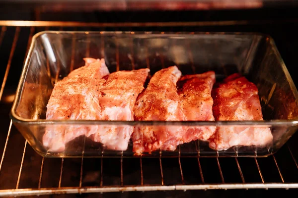 Costolette di maiale con sale, pepe nero e paprica in una teglia di vetro in forno — Foto Stock