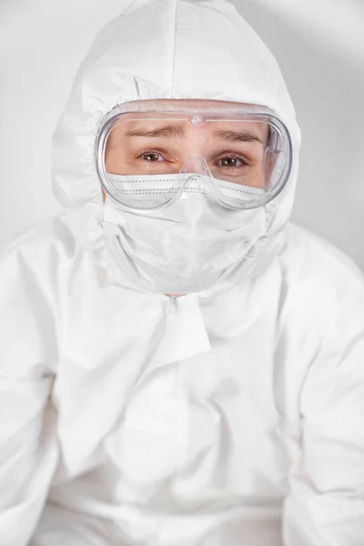 Portrét unaveného lékaře v ochranném obleku, brýle, maska proti bílé stěně — Stock fotografie