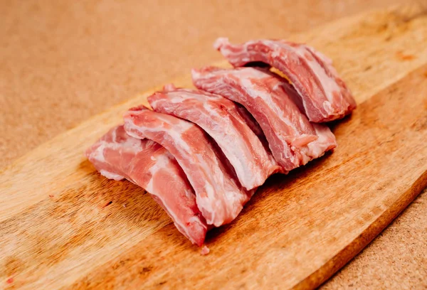Costolette di maiale crude, tagliate a pezzi su un tagliere di legno. — Foto Stock