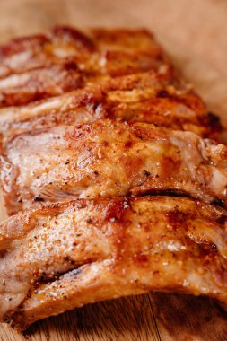 Baharatlı domuz pirzolası ile birlikte ahşap bir kesme tahtasının üzerinde cam bir pişirme çarşafında kızartılmış.